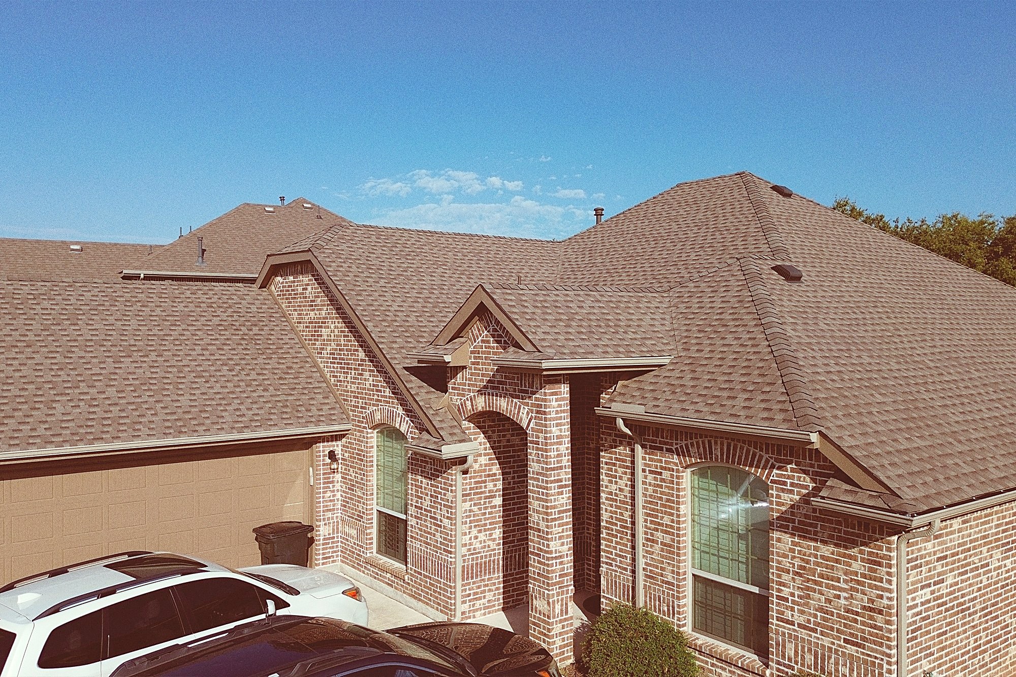 Street view of a brick home with a new brown shingle roof