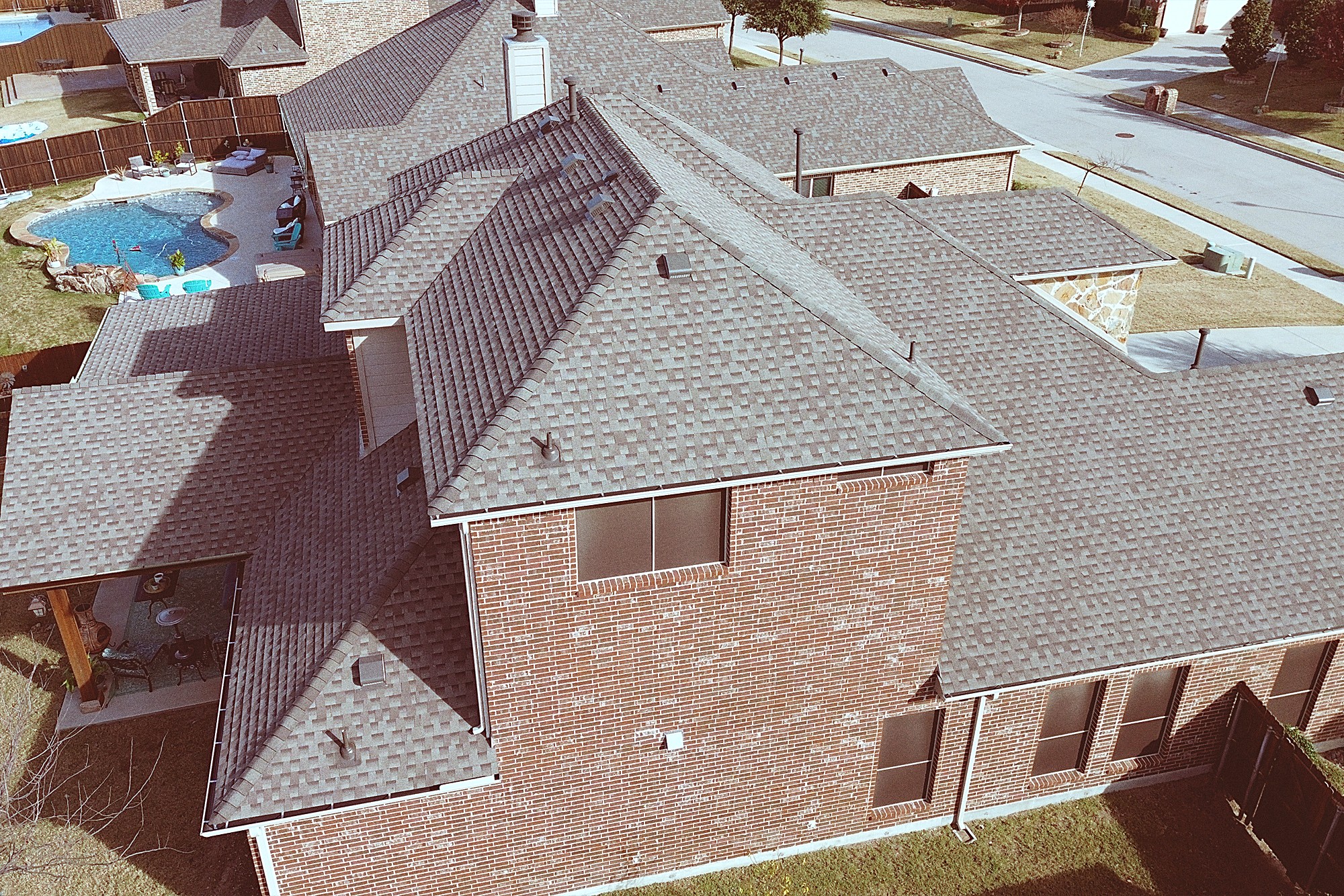 Aerial view of a two-story brick home with a stone accent and a finished hip roof